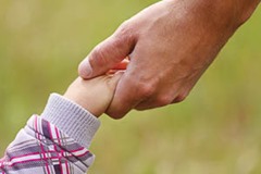 parent holds the hand of a small child