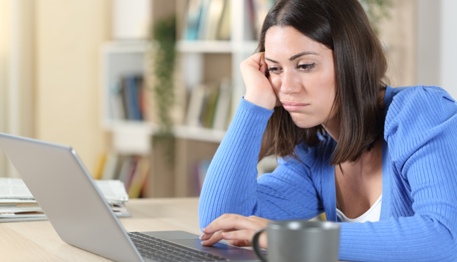 Woman looking dejected and fed up while using a laptop at a table