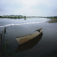 Sunken boat moored to barb wire fence on the River Erne, County Fermanagh.